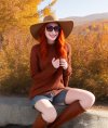 Portray a charming redhead woman basking in the sunshine while sporting cool shades, a chunky ...jpg